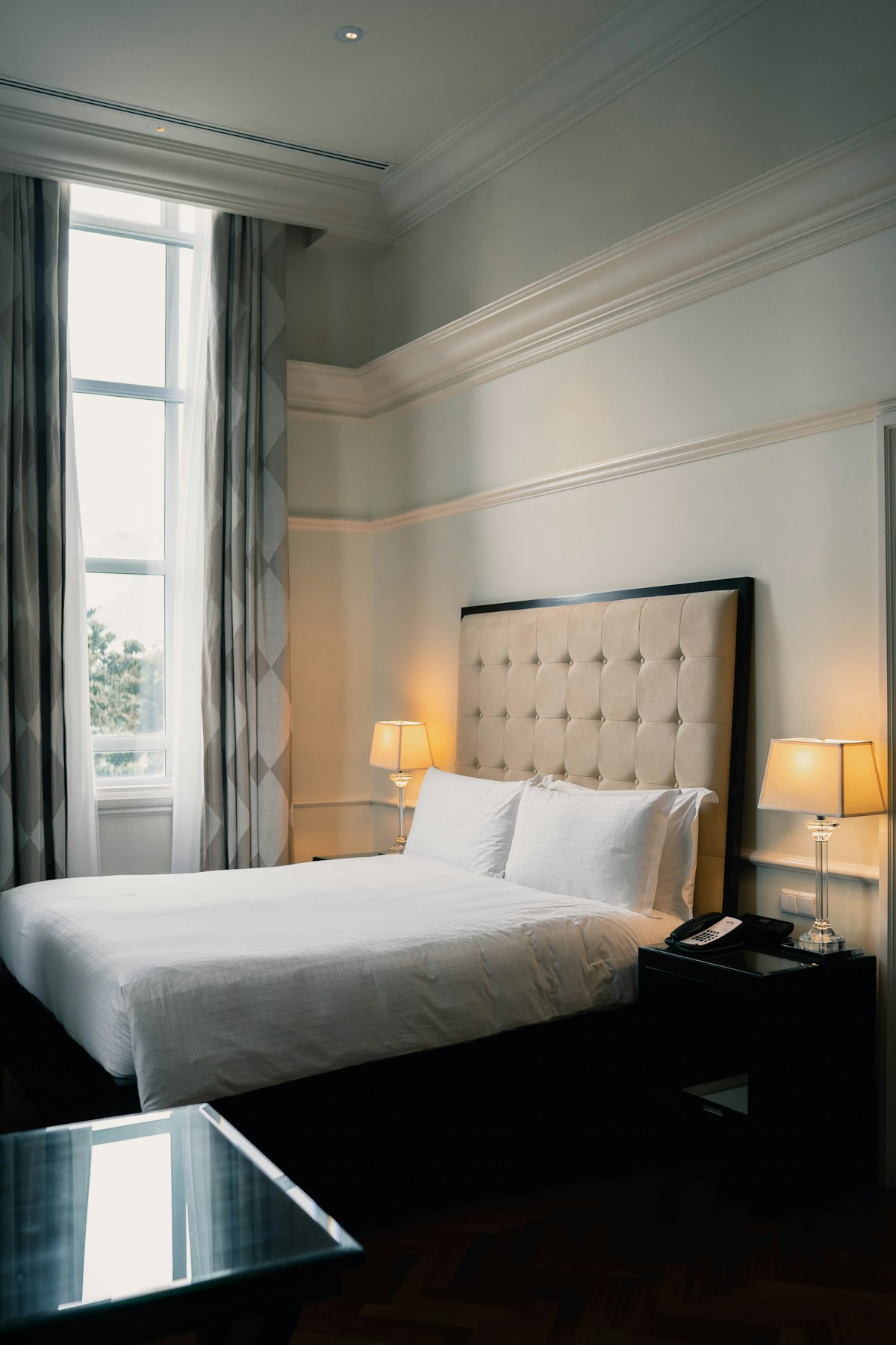 Classic hotel bedroom with a tufted headboard and warm bedside lamps
