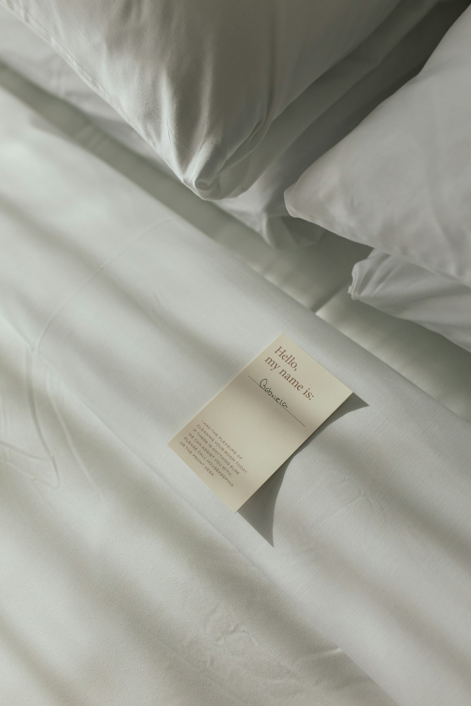 Hotel welcome card resting on white bed linen in soft natural light
